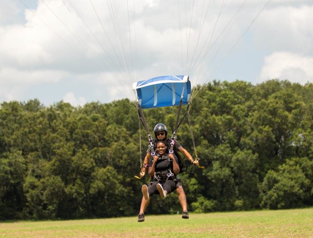 young women comes in for landing after an awesome skydive with a skydive the gulf tandem instructor