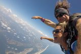 women holds her arms out and smiles while enjoying her beautiful skydive over the gulf shores