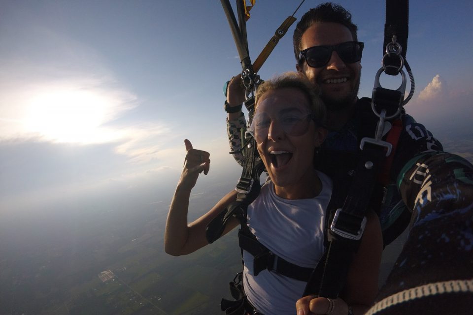 Women wearing white shirt smiling during her skydive at skydive the gulf