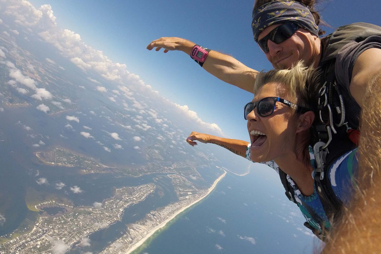 women holds her arms out and smiles while enjoying her beautiful skydive over the gulf shores