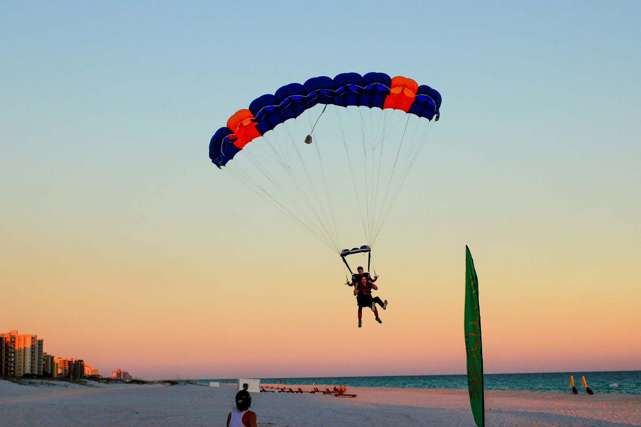 man comes in for beach landing with skydive the gulf tandem instructor