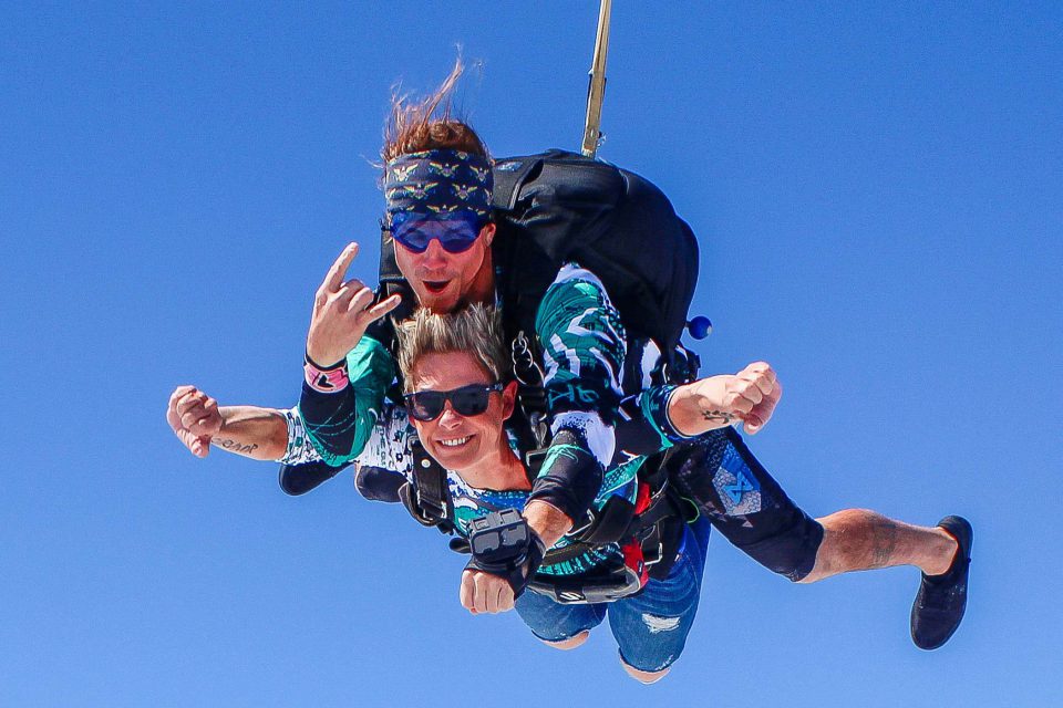 Female tandem skydiver smiles during the free fall portion of her skydive