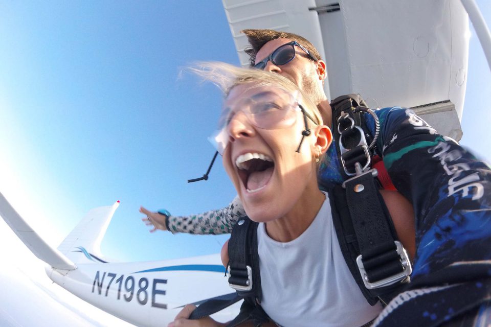 young women wearing a white shirt enjoys the rush of free fall with a skydive the gulf tandem instructor